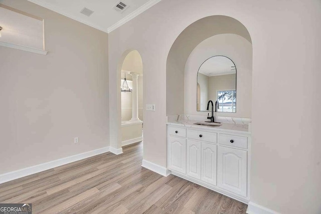 bathroom featuring baseboards, visible vents, ornamental molding, wood finished floors, and vanity