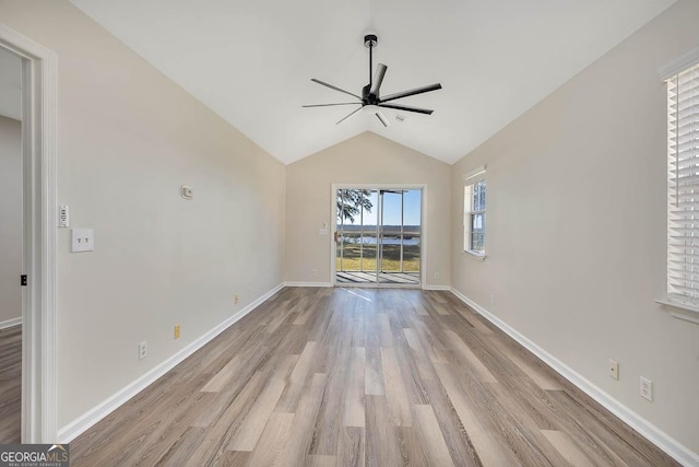 unfurnished living room featuring vaulted ceiling, light wood finished floors, a ceiling fan, and baseboards