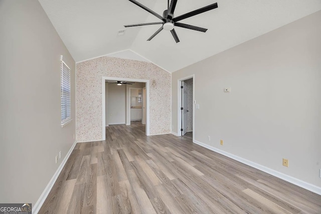 interior space with ceiling fan, baseboards, vaulted ceiling, and wood finished floors