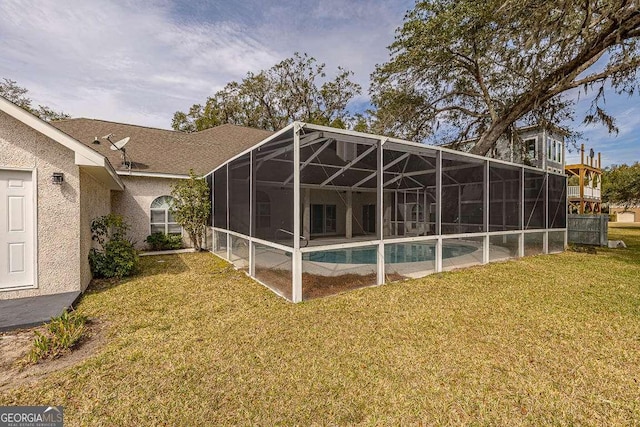 rear view of property with a lawn, an outdoor pool, a lanai, and stucco siding