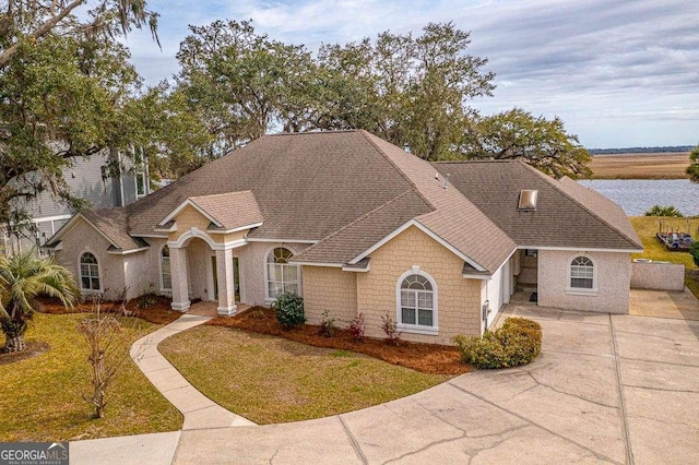 view of front facade featuring a shingled roof, a front lawn, and concrete driveway