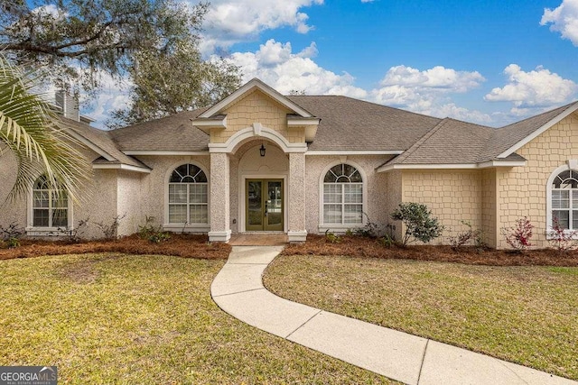 traditional-style house featuring a front yard, french doors, and roof with shingles