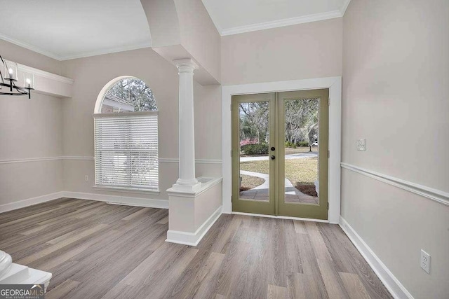 foyer entrance with ornate columns, crown molding, wood finished floors, and french doors