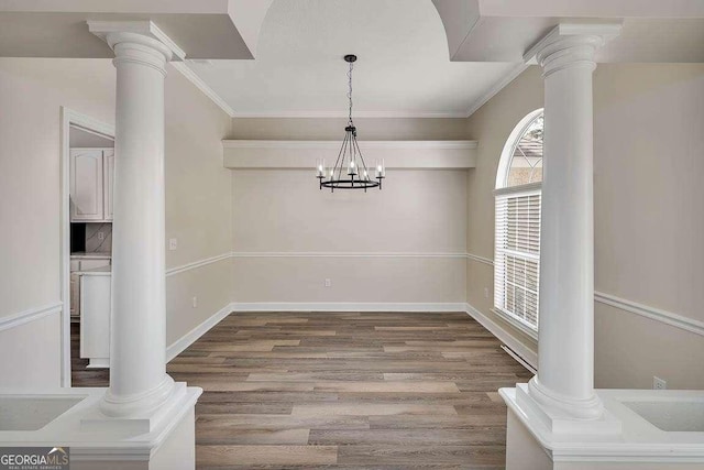 dining area featuring ornate columns, crown molding, and wood finished floors