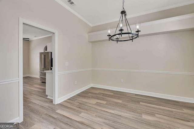 unfurnished dining area featuring ornamental molding, a notable chandelier, baseboards, and wood finished floors