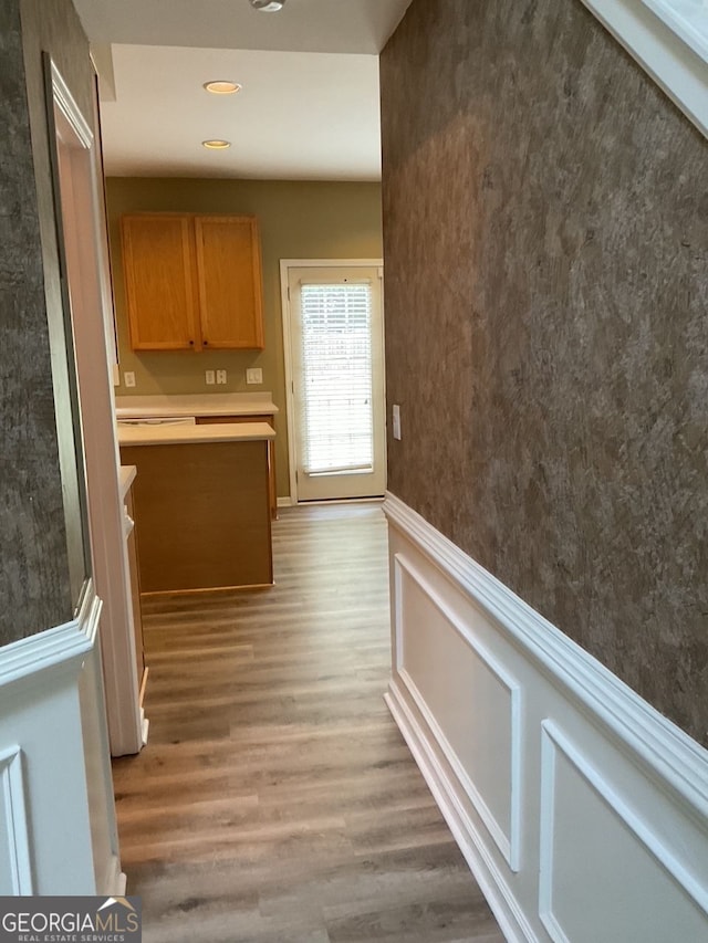 hallway with light wood finished floors and wainscoting