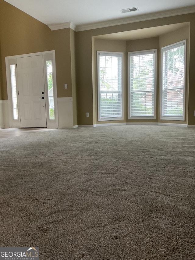 unfurnished living room featuring ornamental molding, carpet, and visible vents