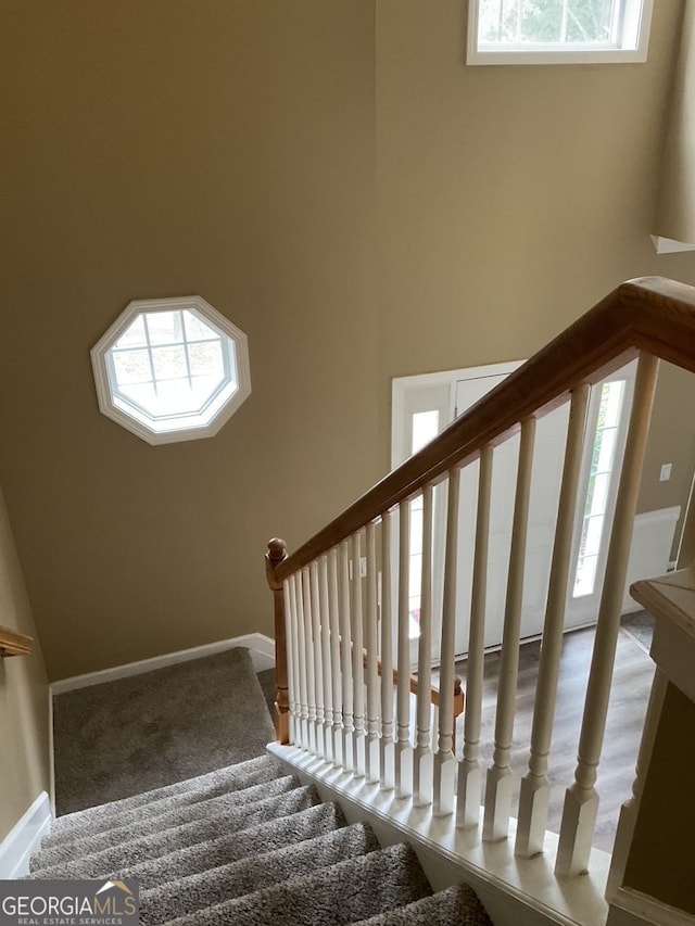 stairway with plenty of natural light and baseboards