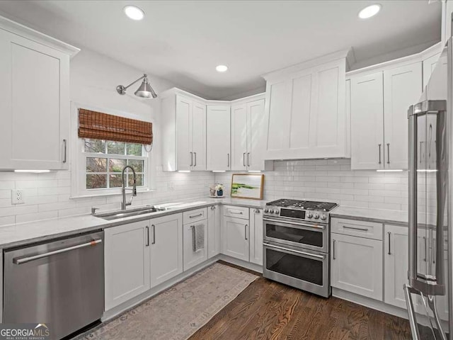 kitchen with dark wood-style flooring, tasteful backsplash, appliances with stainless steel finishes, white cabinetry, and a sink