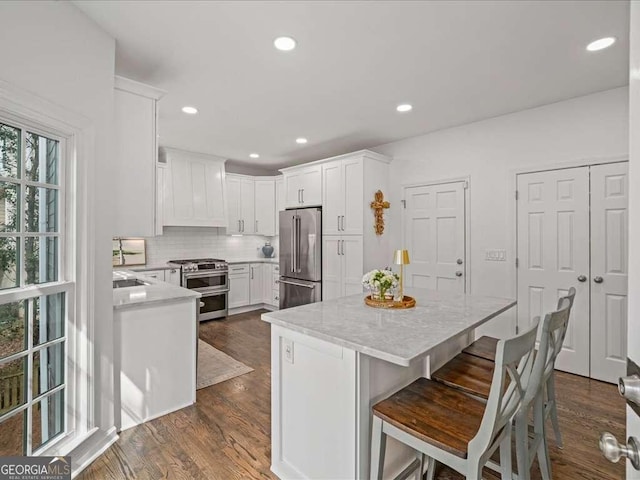 kitchen featuring premium appliances, dark wood-style flooring, a kitchen island, and white cabinetry