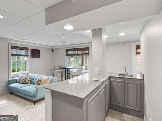 kitchen with a wealth of natural light, gray cabinets, a sink, and ornate columns