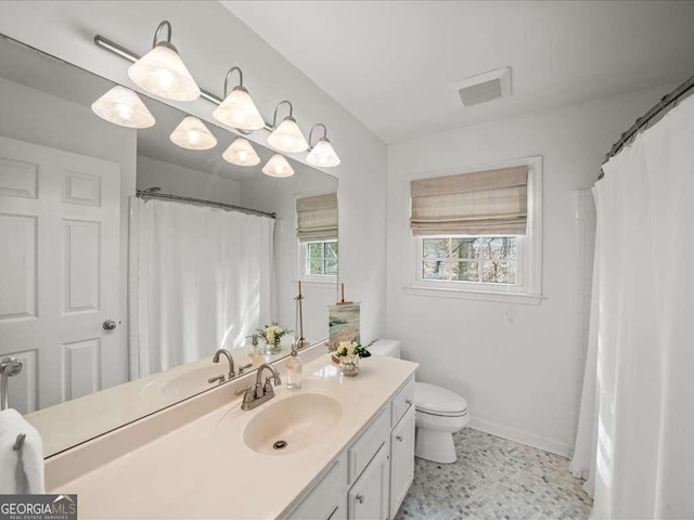 bathroom with toilet, vanity, visible vents, and baseboards