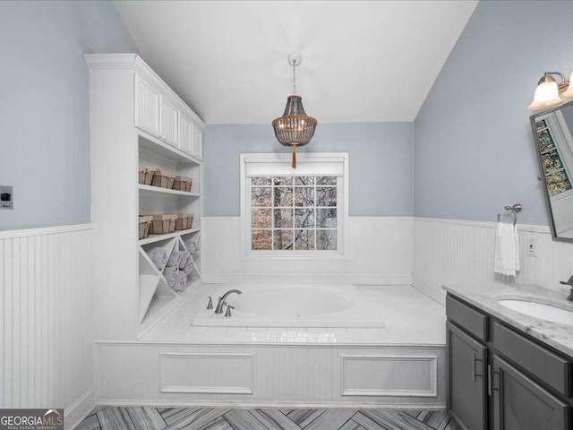 full bath featuring a wainscoted wall, a bath, and vanity