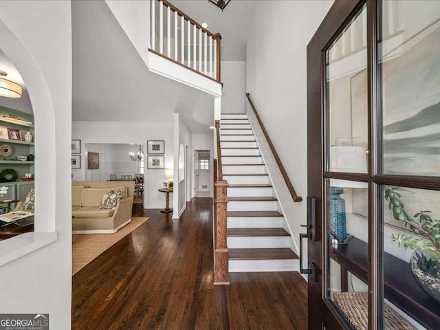 foyer with baseboards, stairway, arched walkways, and wood finished floors