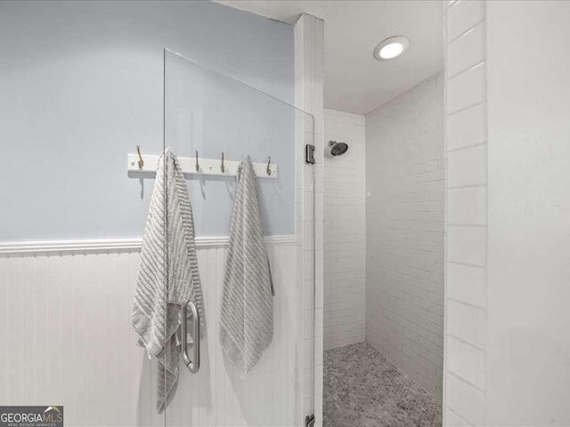 bathroom featuring a wainscoted wall and walk in shower