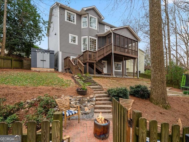 rear view of property with fence private yard, an outdoor structure, a sunroom, stairs, and a patio area