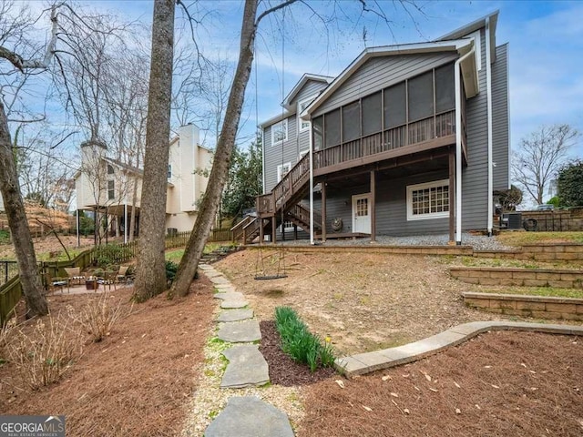 back of property featuring a sunroom, a patio, stairway, and fence