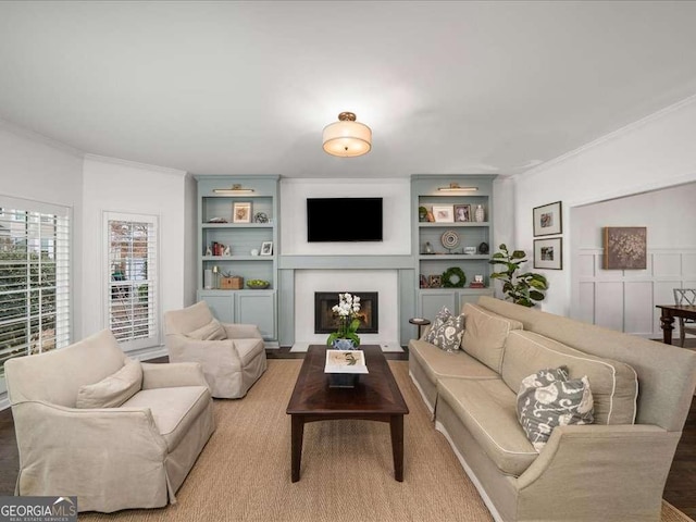 living area with ornamental molding, a fireplace, and built in shelves