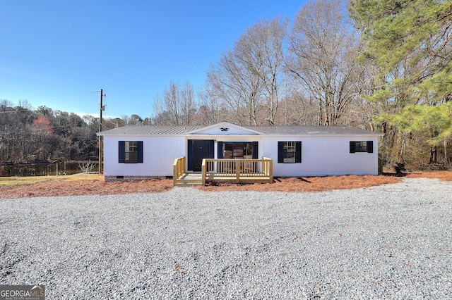 view of front of house with crawl space, metal roof, and gravel driveway