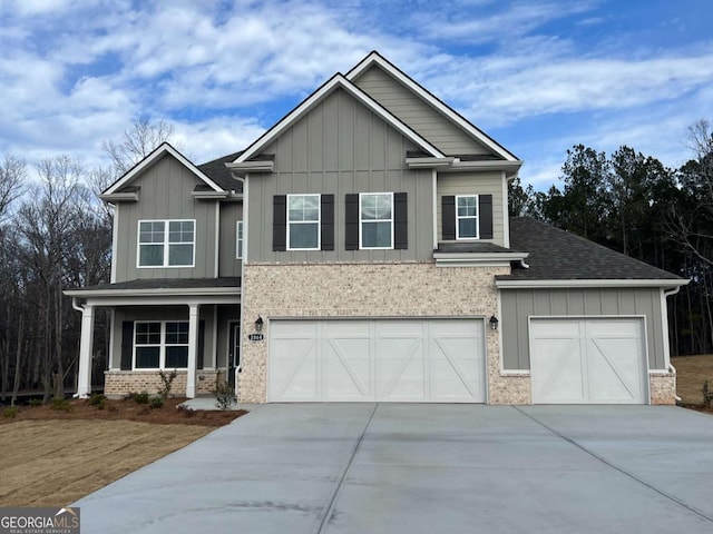 craftsman house with board and batten siding, concrete driveway, brick siding, and a porch