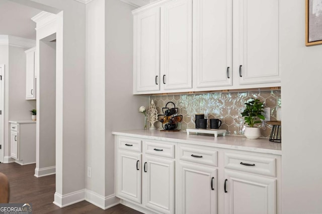 bar with baseboards, decorative backsplash, dark wood finished floors, and ornamental molding