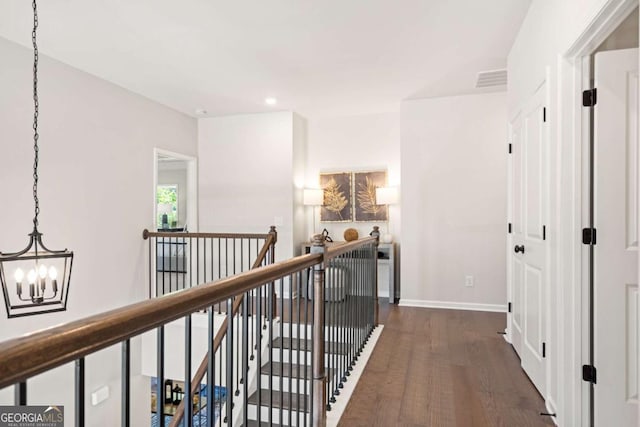 hall featuring dark wood-style flooring, a notable chandelier, recessed lighting, an upstairs landing, and baseboards