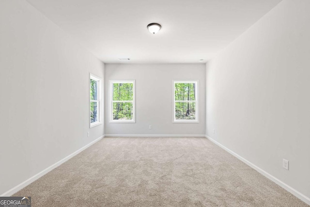 spare room with carpet floors, visible vents, and baseboards