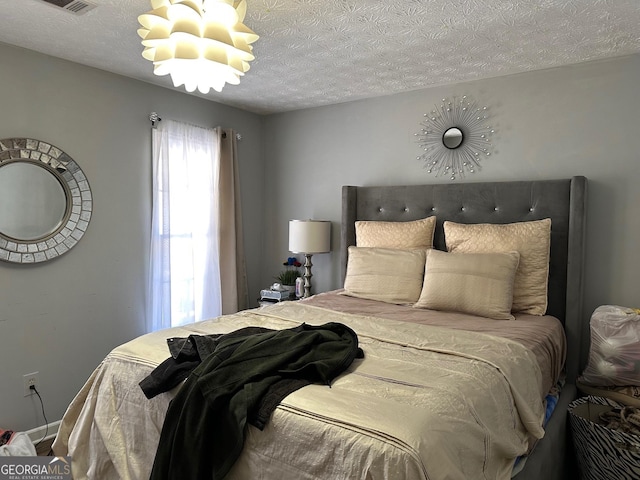 bedroom with an inviting chandelier, baseboards, and a textured ceiling