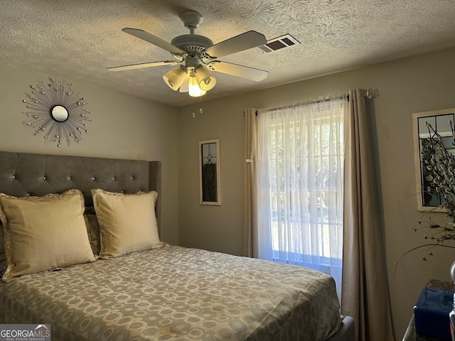 bedroom with a ceiling fan, visible vents, and a textured ceiling