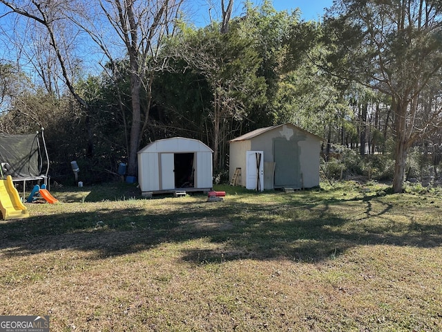 view of yard with a storage shed, a trampoline, and an outbuilding