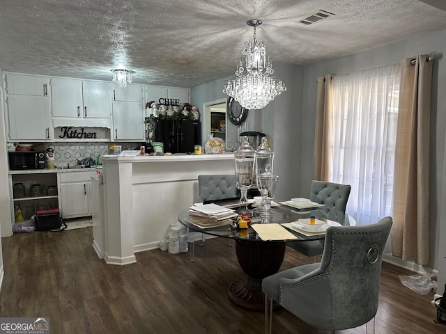 dining room featuring dark wood-style floors, a textured ceiling, visible vents, and a notable chandelier