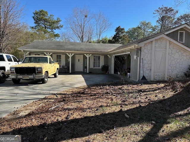 ranch-style home with an attached garage, driveway, and stone siding