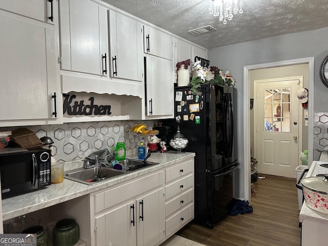 kitchen with a sink, visible vents, white cabinets, light countertops, and black appliances