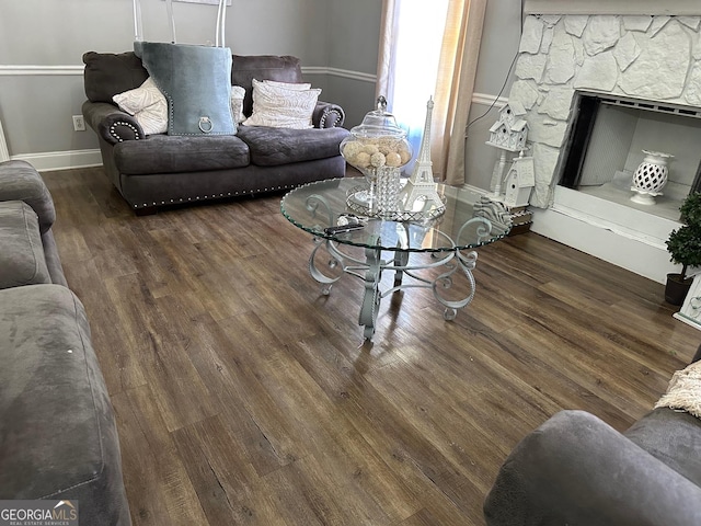 living area featuring a fireplace, baseboards, and wood finished floors