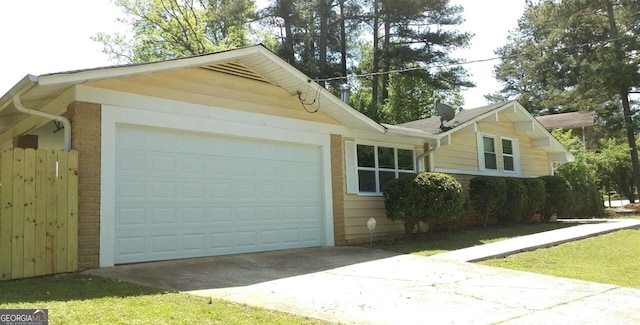 view of side of home with an attached garage, concrete driveway, and brick siding