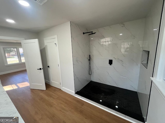 bathroom with a marble finish shower, baseboards, and wood finished floors
