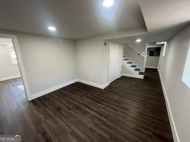 basement with visible vents, stairs, baseboards, and dark wood-style flooring