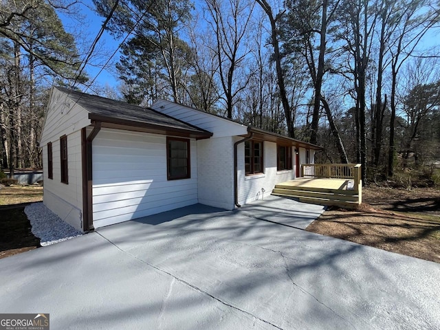view of home's exterior with a patio area, brick siding, and a deck