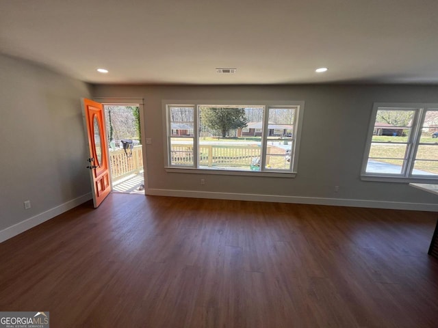unfurnished living room with dark wood-style floors, visible vents, recessed lighting, and baseboards