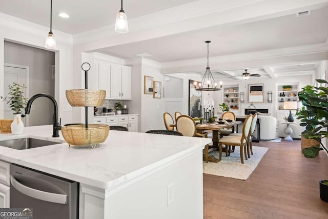 kitchen with wood finished floors, a sink, white cabinetry, dishwasher, and pendant lighting