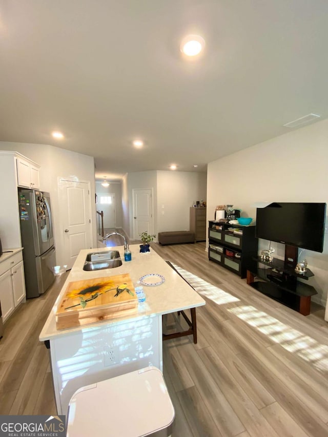 kitchen with light countertops, white cabinets, a sink, and freestanding refrigerator