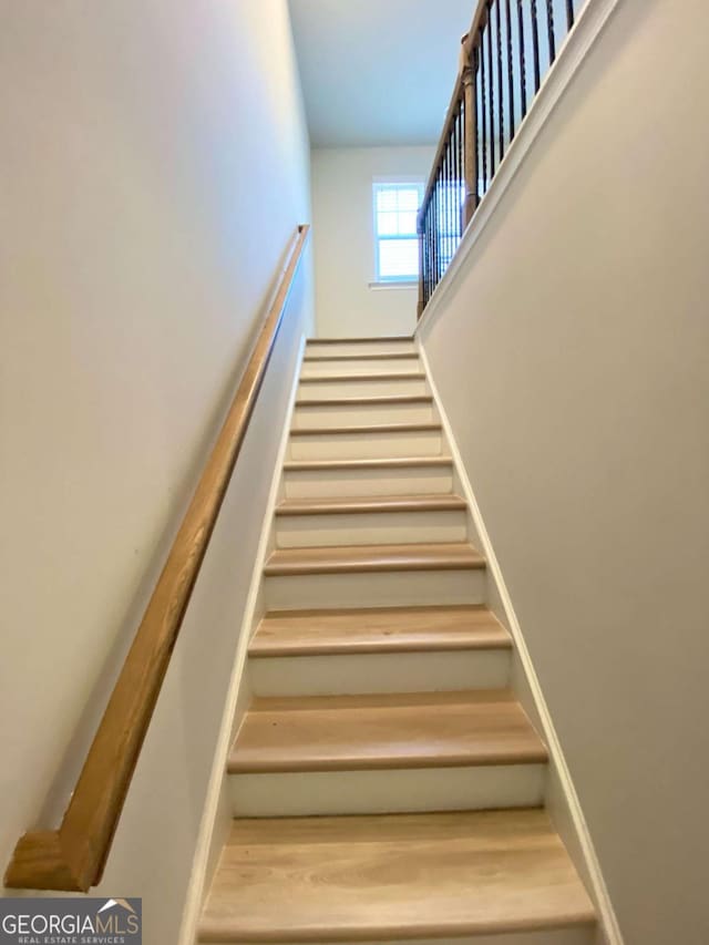 stairway featuring a towering ceiling and baseboards