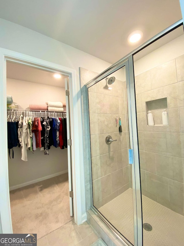 full bathroom featuring a stall shower, a spacious closet, and tile patterned floors