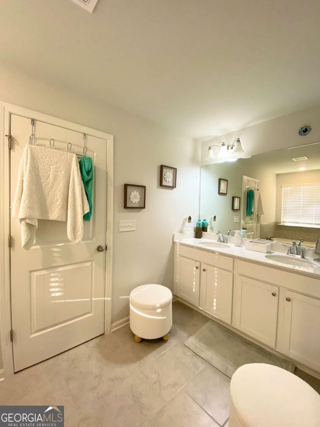 full bath featuring double vanity, a sink, and toilet