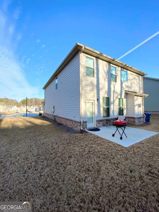 rear view of house featuring brick siding, a lawn, and a patio area