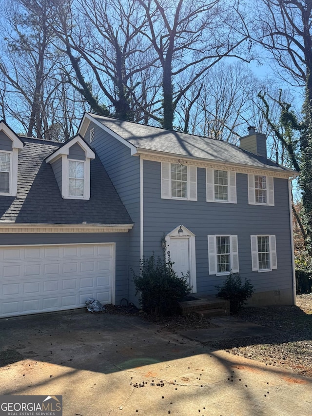 colonial-style house with driveway, a shingled roof, a chimney, an attached garage, and crawl space