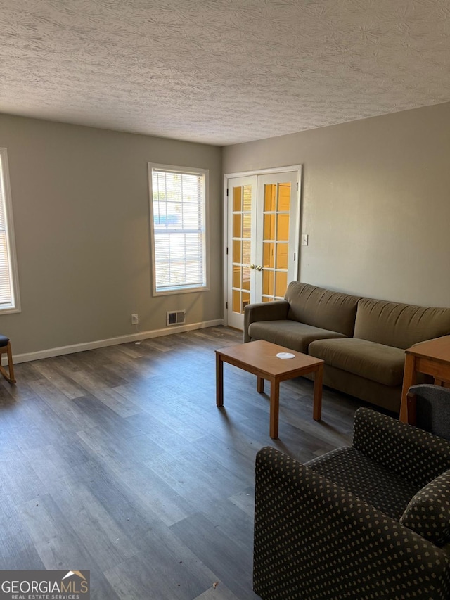 unfurnished living room featuring visible vents, baseboards, wood finished floors, a textured ceiling, and french doors