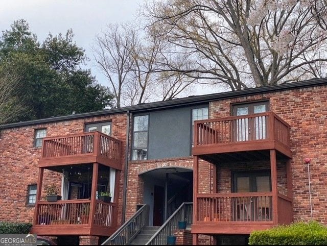 back of house with a balcony and brick siding