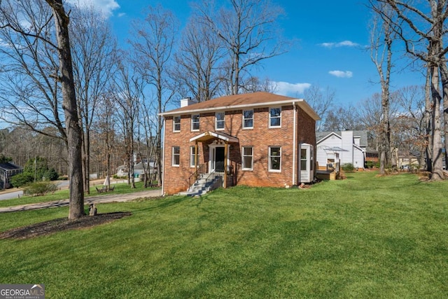 colonial house featuring brick siding, a chimney, and a front lawn