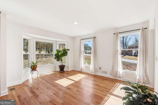 unfurnished room featuring visible vents, baseboards, and wood finished floors